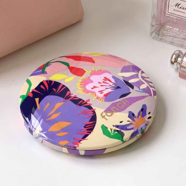 Mini Taylor Lighted Compact Mirror By Fancii & Co. in Brandi Raines Bloom Lifestyle Image- the mirror is closed and sitting on a table