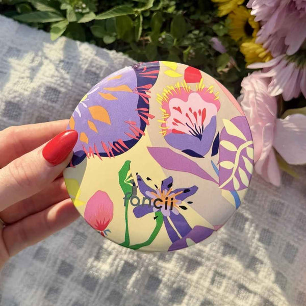 Mini Taylor Lighted Compact Mirror By Fancii & Co. in Brandi Raines Bloom Lifestyle image, held outside over a picnic blanket in a garden.