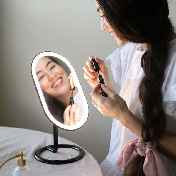 Woman using Fancii's vera lighted vanity to apply skincare in Black