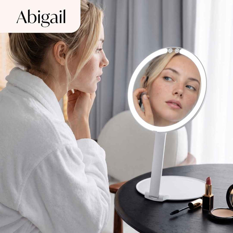Abigail Lighted Compact in White Set up on desk and being used by model to apply lipstick