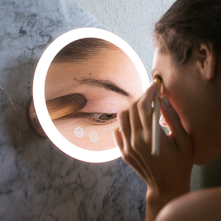 Woman using Fancii Lana 10x magnifying mirror with lights in Rose Gold