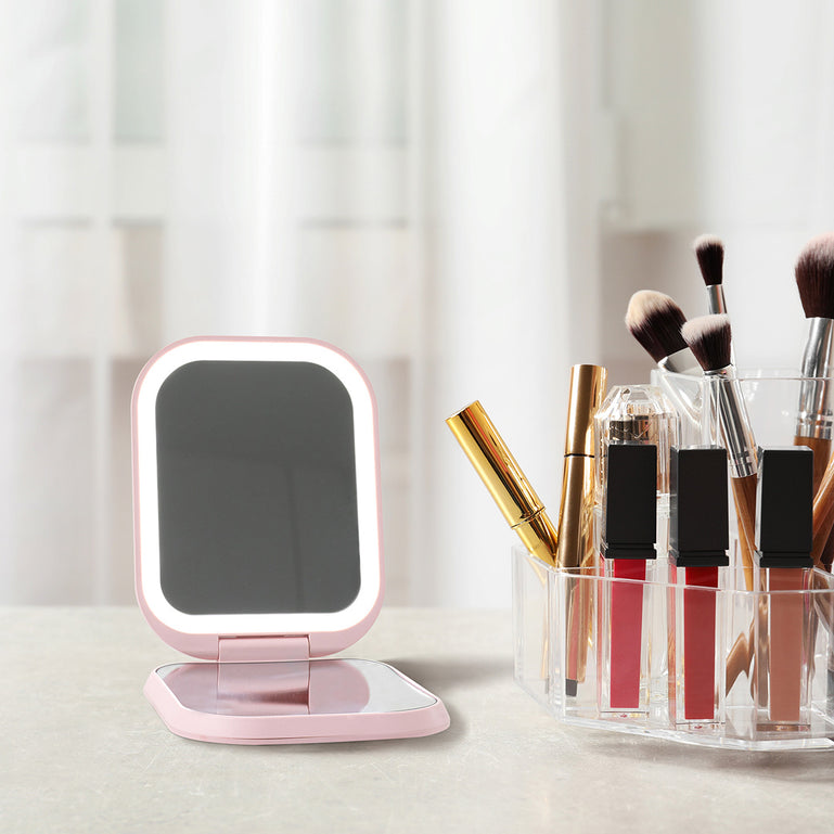 Mica Lighted Compact with built-in powerbank in Strawberry Cream color by Fancii and Co sits on a desk with lipstick and makeup brushes.