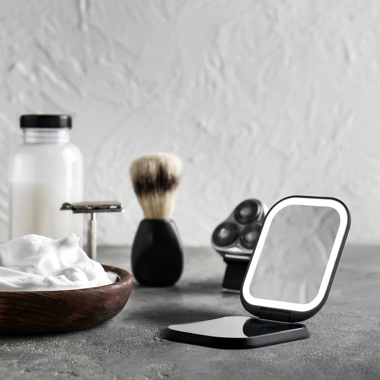 Mica Lighted Compact with built-in powerbank in Black Sesame color by Fancii and Co. Mica sits on a granite counter amongst shaving tools.
