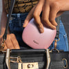 Woman putting Mila lighted compact into designer purse Pink