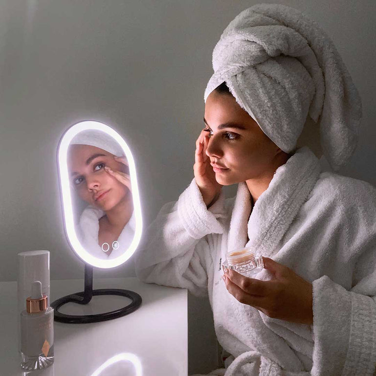 Woman using Fancii's vera lighted vanity to apply skincare in Black