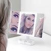 Woman using the Zora tri fold vanity mirror with LED lights by Fancii and Co with multiplle magnification options